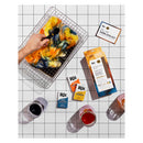 Yarn dyeing kit with colorful yarn on a grid surface, including Rit dye packets and jars.