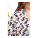 Multicolored crocheted shawl worn by a person on a white background