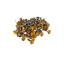 A pile of small oval amber-yellow rhinestones with silver metal settings and backing pins, photographed on a plain white background.