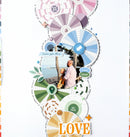 A vertical scrapbook page layout featuring layered circular paper fans, green leaves, a small photo of a couple by the beach, decorative text labels, and the word 'LOVE' in orange at the bottom, all arranged on a white background.