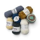 A pile of Poppy Crafts yarn skeins in multiple colors, including blue, mustard yellow, navy, cream, and a variegated green, brown, and beige pattern, on a white background.