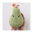 Hand holding a green crochet pear with a smiling face on a white background