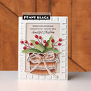 A handmade Christmas greeting card featuring a white embossed border, a central beige panel with the text 'Where light lingers and moments shine - wishing you a beautiful Christmas', and a layered gift box design with green leaves, red berries, and a metallic rose-gold bow. The card is branded with 'Penny Black' and 'papercrafting with Penny Black' at the top.