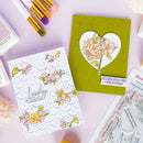 Two floral cards on a pink surface with craft supplies.