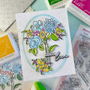 Card with floral design and 'Sending love' text, surrounded by stamping tools on a light blue background.