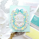 Card with decorative elements and text on a light blue background, surrounded by stationery items.