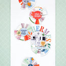 A collection of colorful scrapbook paper circles and layered paper designs arranged on a white background, featuring retro text like 'what a delight', 'reasons to be happy', and 'HERMES', alongside small illustrations and pastel patterned accents.