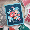 Colorful floral card with 'Sending love' text on a crafting table with stamps and dies.