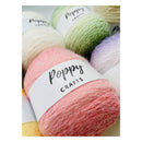Close-up of several skeins of Poppy Crafts yarn with white paper labels, including pastel cream, mint green, coral pink, lavender, and pale yellow.