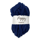 A skein of chunky, plush chenille yarn in a deep navy blue color, wrapped with a white paper label that reads 'Poppy CRAFTS'. The yarn is photographed on a clean, solid white background.