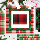 A styled flat-lay of Christmas-themed plaid paper sheets and cardstock designs, featuring red, green, and black tartan patterns with holiday decorations like pine branches, candy canes, and ornaments on a white background.