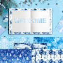 A flat-lay display of winter-themed paper products, featuring an open notebook with a blue patterned border and 'WELCOME' spelled out in decorative letters, surrounded by matching patterned paper sheets and holiday decorations on a light blue background.