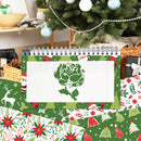A spiral-bound notepad with a green rose illustration on the cover is displayed in a festive Christmas setting, surrounded by patterned wrapping paper and holiday decorations.