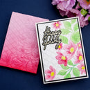 Card with 'Happy Spring' text and floral design next to a pink floral embossed envelope on a dark blue background.