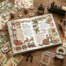 An open vintage-style collage book on a rustic wooden table, surrounded by Christmas-themed paper scraps, washi tape, wooden ornaments, a small bottle, and other holiday decor. The book pages feature festive illustrations, postcard-like stamps, and handwritten holiday memories.