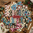 A flat lay of multiple Christmas-themed paper craft sheets featuring cute dog illustrations in winter outfits, arranged on a wooden surface with crafting props like scissors, twine, green ribbon, pinecones, and a wooden spatula. A central label reads 'Cuddle' and '12 Different Designs 2.