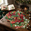 Stack of Christmas cards on a wooden table with a fireplace and decorations in the background