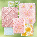 Set of silicone molds with floral, bow, and waterdrop patterns on a green background