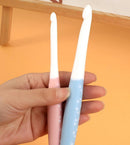 Hand holding two small, light-colored objects against a yellow background