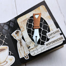A close-up of a decorative handmade paper journal page with a vintage-inspired layout. The page features a black background with layered cream and beige textured paper inserts, a central fountain pen nib and cap design with a small heart on the cap, a vintage woman silhouette sticker, a coffee cup illustration, and Polish text stickers reading 'ZAPISANE' and 'WSPOMNIENIA'.