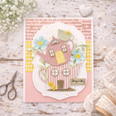 Card with a decorative house and flowers on a wooden surface with text and a heart.