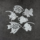 A set of seven silver metal fish-shaped wall hooks or ornaments arranged in a circle on a dark textured background.