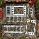 Five white metal film strip frames of different sizes arranged on a textured tree bark background.
