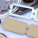 A pair of craft dies or templates shown on a white textured surface with decorative fabric and lace props. One piece is a white metal stamping or cutting die, and the other is a flat tan paper or cardstock template piece with stitched border details and a circular cutout.