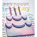 A close-up of a pastel birthday card featuring a layered cake design with purple candles, surrounded by embossed lettering on a white cardstock background.