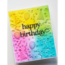 A handmade birthday card with a vibrant yellow-to-blue gradient background, featuring embossed party-themed designs like balloons, stars, and party hats. The words 'happy birthday' are written in black cursive across the center.