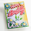 A handmade square birthday card featuring 3D layered paper flowers, green leaves, a small bird, and the words 'HAPPY Birthday' in red and white script on a pastel yellow and lavender background.