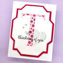 A handmade greeting card with a white base, featuring a layered red scalloped border and a central pink polka-dot letter 'T' with the words 'thinking of you' in black script and gray scribble lines.