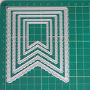 A set of silver metal embossing or stamping dies arranged in a nested chevron pattern on a green cutting mat with grid lines.