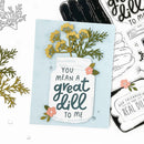 A handmade greeting card featuring a mason jar design with the phrase 'YOU MEAN A great dill TO ME' in dark teal script, decorated with yellow flowers and green foliage. The card is styled on a white background alongside other crafting elements, including clear stamps and gray die-cut embellishments.