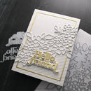 White card with 'Hello, friend' text and floral design, surrounded by metal cutting dies on a dark surface.