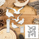 A set of metal seagull die-cut shapes in silver and white, displayed on a rustic wood slice background alongside pinecones. A small inset in the bottom right corner shows the reverse side of the metal pieces with engraved text and line details.