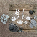 White and silver metal nail art stamping dies arranged on a rustic wooden board with decorative stones, set against a burlap-textured background.
