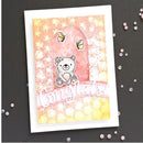 A handmade congratulations card featuring a cute cartoon bear, butterflies, and a 'Congrats!' banner, displayed on a dark textured background with scattered pink confetti.