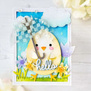 A handmade layered greeting card featuring a yellow chick holding a gray umbrella, with the word 'hello' in white script, set against a blue sky background with clouds, flowers, and grass.