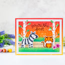 A handmade greeting card featuring a zebra and a cartoon tiger in a forest scene with the text 'you're the best'. The card has a red border, a white inner border, and a yellow-orange outer border, and is displayed on a white surface with blurred flowers in the background.