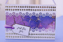 A handmade greeting card with a purple and blue marbled background, decorated with white floral cutouts, metallic gold stitched borders, and a white tag that reads 'just for you'.