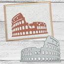 A metal die-cut template of the Colosseum shown in front of a sample stamped card featuring the same Colosseum design in terracotta on textured white cardstock, set against a white wood plank background.