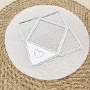 A metal die-cut craft template set featuring geometric frames and a dotted heart outline, displayed on a round beige paper circle over a woven straw placemat.