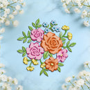 A flat-lay of a colorful floral arrangement made from layered paper or felt flowers and leaves, centered on a light blue marble surface with white baby's breath flowers framing the edges.
