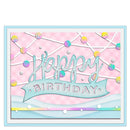 A square handmade-style birthday card with a pastel pink patterned background, a light blue border, and a central blue banner reading “Happy Birthday.” Decorative white lines, iridescent pastel dots, and layered paper textures create a playful, celebratory design.