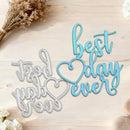 Decorative metal cutouts with 'it was a good world to live in' and 'best day ever' text on a wooden surface with flowers.