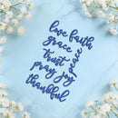Blue cursive wall art reading 'love faith grace trust prayer joy thankful' arranged on a light blue marble background with white baby's breath flowers in the corners.