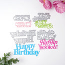 A flat-lay of multiple laser-cut metal birthday cake toppers in various colors (silver, pink, blue, green) on a white background, styled with pink flowers and green leaves.