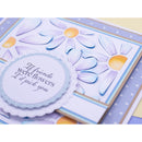 A close-up of a handmade greeting card featuring layered die-cut daisy flowers in lavender, blue, and white with yellow centers, plus a scalloped circular label that reads, 'If friends were flowers I'd pick you.'.