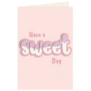A pink greeting card with an envelope partially visible at the top, featuring the text 'Have a Sweet Day' in layered pink and white bubble lettering with glittery fill.